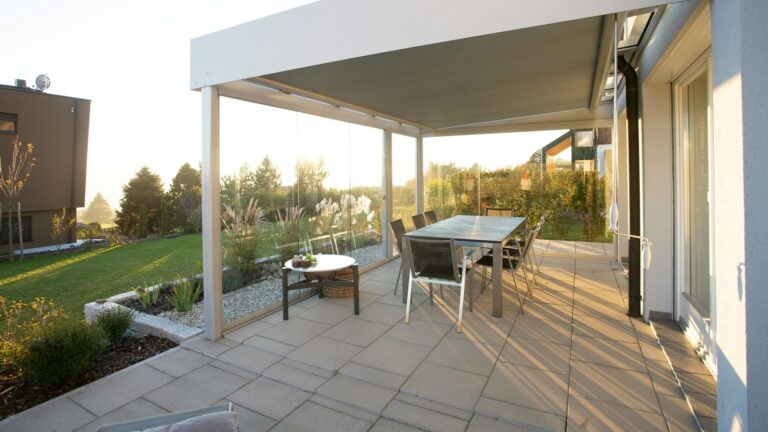 Strak aangelegd terras met grote tegels, moderne overkapping en tuinmeubilair, ideaal voorbeeld van terras aanleggen